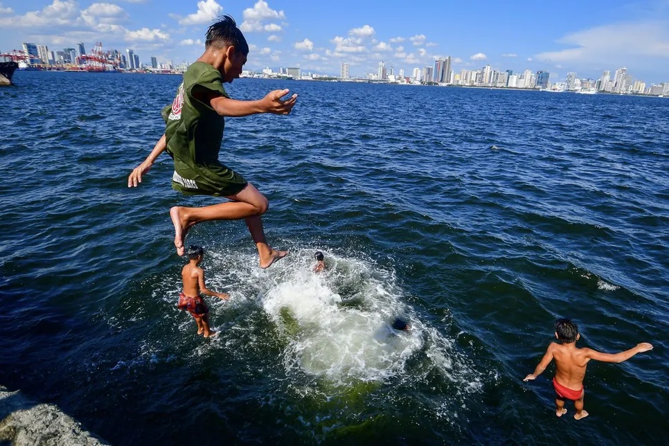 Residents spend time along a breakwater in Manila on April 28, 2024.