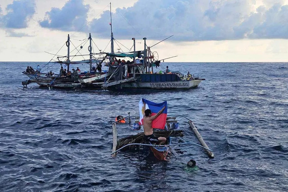 In this photo provided by Atin-Ito/Akbayan Party, a fisherman raises a Philippine flag on his boat as activists and volunteers from a nongovernment coalition called Atin Ito Coalition, sailed at the West Philippine Sea on Thursday May 16, 2024.