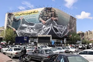 Vehicles drive past a large billboard reading "The Strait of Hormuz remains closed" as people gather in Tehran's Revolution Square after the United States and Iran agreed to a two-week ceasefire, on April 8, 2026. Atta Kenare, AFP
