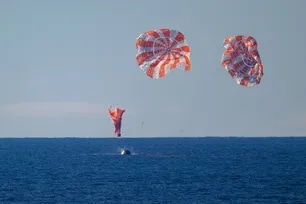 In this handout photo provided by NASA, NASA's Orion spacecraft with Artemis II crewmembers NASA astronauts Reid Wiseman, commander; Victor Glover, pilot; Christina Koch, mission specialist; and CSA (Canadian Space Agency) astronaut Jeremy Hansen, mission specialist aboard is seen as it lands in the Pacific Ocean off the coast of California, Friday, April 10, 2026. Bill Ingalls, NASA via Getty Images/AFP