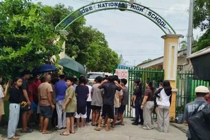 Students and their parents wait for permission from school authorities to enter the school compound at the gate of San Jose High School in Tacloban City, Leyte province, a day after a shooting incident. Two students opened fire June 22 inside a school in the central Philippines, a rare campus shooting that killed three teens and wounded seven others, police said. Noel  Sianosa, AFP
