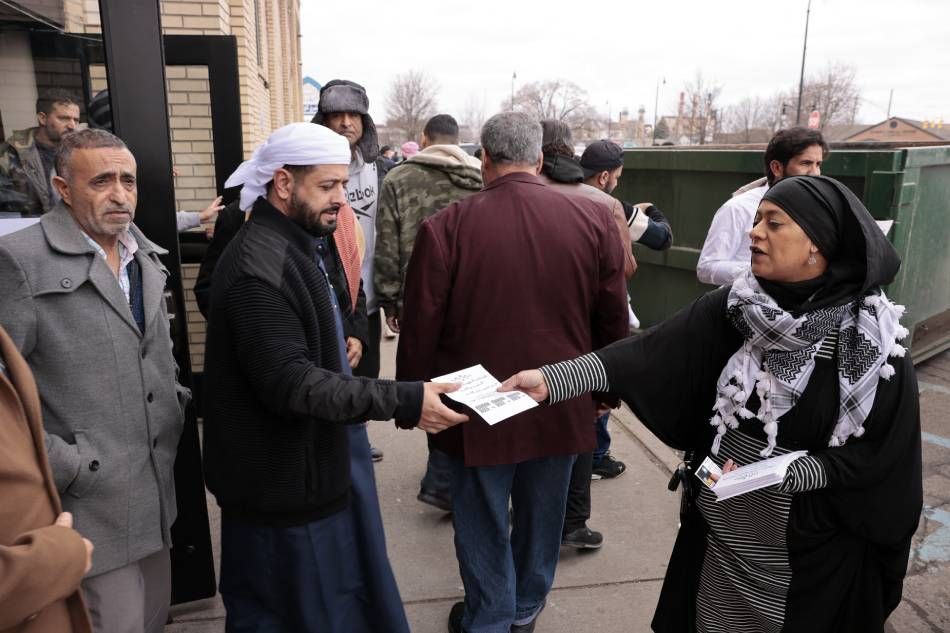 Samra'a Luqman (R) hands out fliers outside of the American Moslem Society Mosque to ask voters not to vote for President Joe Biden after Friday prayers in Dearborn Heights, Michigan, on February 16, 2024. Jeff Kowalsky, AFP