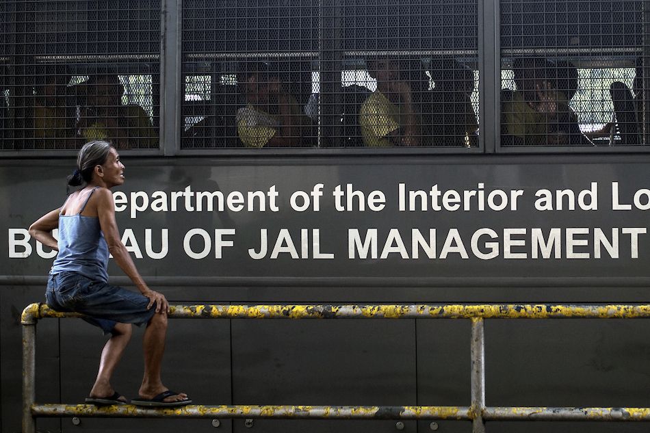 A woman talks to her nephew sitting inside a Bureau of Jail and Penology Management (BJMP) bu, as he and other inmates make their way to attend a hearing in Manila on October 19, 2017. Noel Celis, AFP