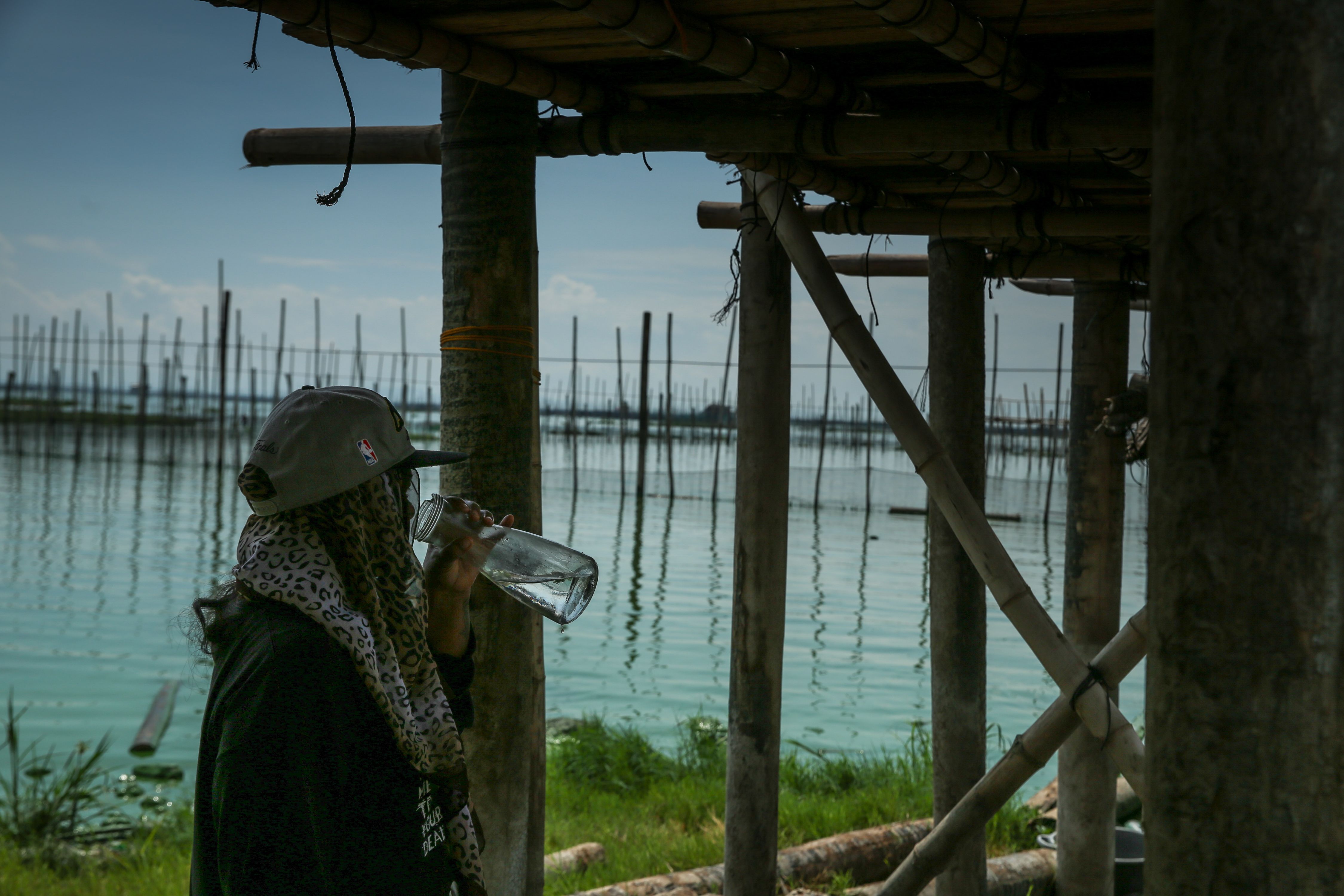 A volunteer takes a break and drinks water near the banks of the Laguna Lake in Muntinlupa City on June 10, 2019. Jonathan Cellona, ABS-CBN News/File