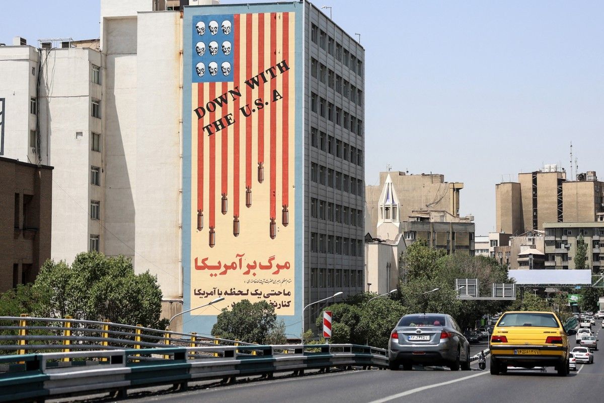 Commuters drive along a bridge near a building bearing a landmark anti-US mural in Tehran, on June 22, 2025. AFP