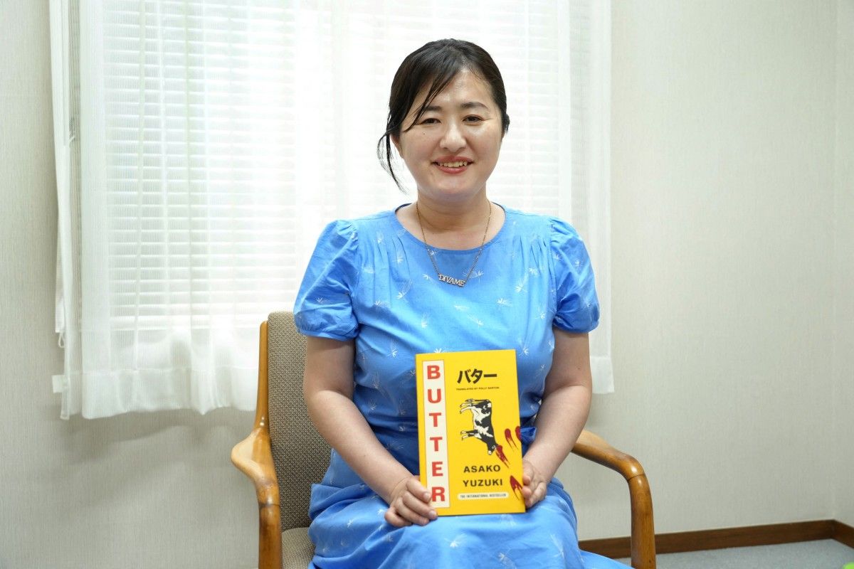 This photo taken on June 24, 2025 shows Japanese author Asako Yuzuki posing with her novel 'Butter,' translated into a foreign language, during an interview with AFP in Tokyo. Kazuhiro Nogi, AFP